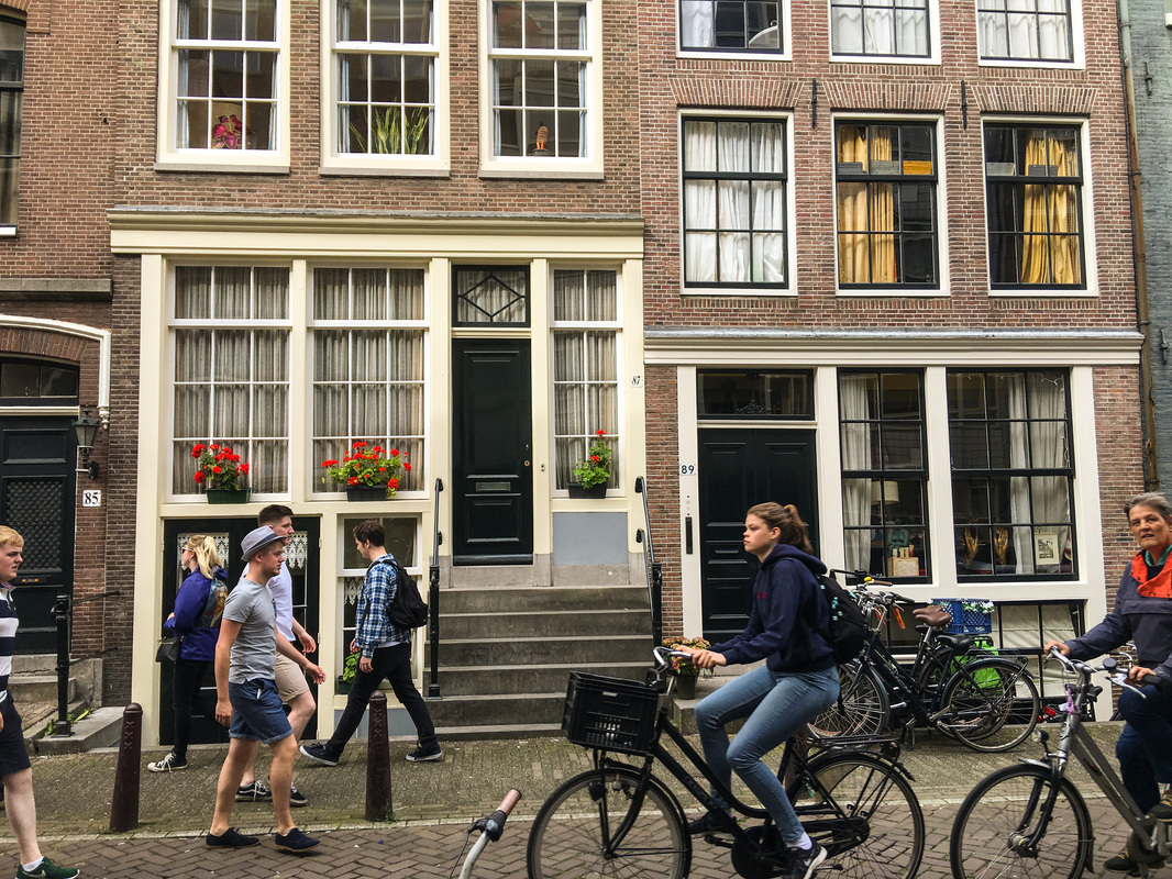 Rainy, Zany Amsterdam / bicyclists & pedestrians / Karen McCann / EnjoyLivingAbroad.com